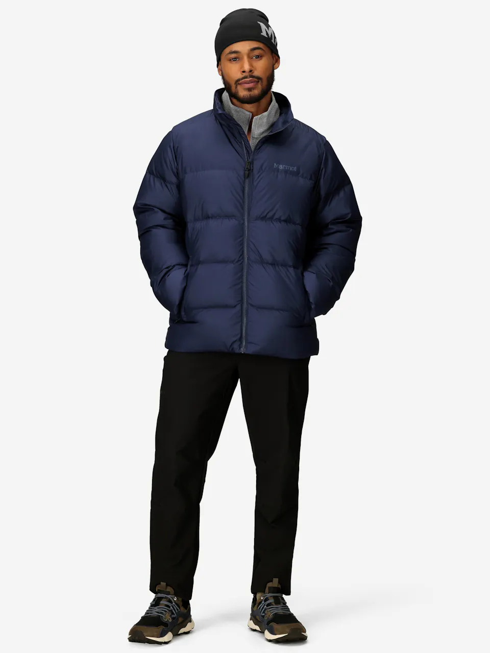 Men's blue puffer jacket with zip closure and side pockets, paired with black pants and athletic sneakers.
